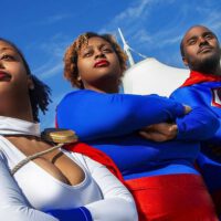 Two black girls as supergirl with black superman
