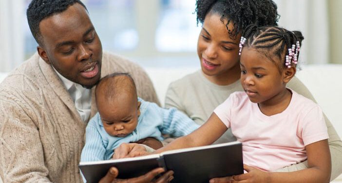 family reading to baby son and daughter