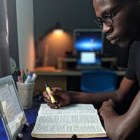 Black Man Reading Bible And Using Tablet